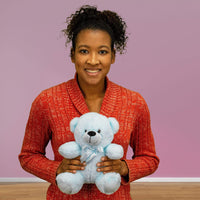 A woman holds a light blue bear that's 9 inches tall while sitting
