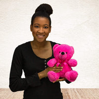 A woman holds a pink bear that is 9 inches tall while sitting