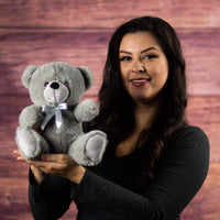 A woman holds a gray bear that is 9 inches tall while sitting