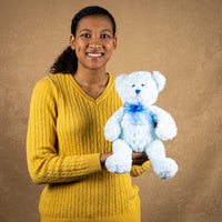 A woman holds a blue bear that is 14 inches tall while standing