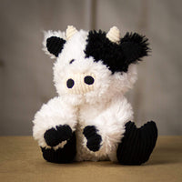 A scruffy black and white cow that is 9.5 inches tall while sitting