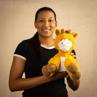 A woman holds a scruffy orange and white giraffe that is 9.5 inches tall while sitting