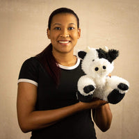 A woman holds a scruffy black and white cow that is 9.5 inches tall while sitting