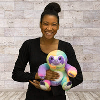 A woman holds a rainbow sloth that is 11 inches tall while sitting