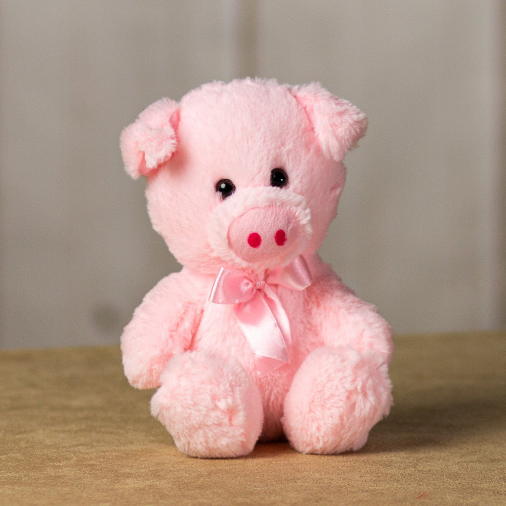 A light pink pig that is 7 inches tall while sitting wearing a matching bow