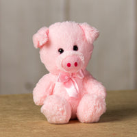 A light pink pig that is 7 inches tall while sitting wearing a matching bow