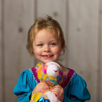 A little girl holding a psychedelic giraffe that is 10.5 inches tall while sitting shiny hooves and sparkly eyes