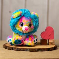 A psychedelic lion that is 10 inches tall while sitting with shiny paws , blue fluffy mane, and sparkly eyes next to wooden blocks