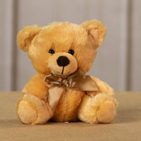 A beige bear that is 6 inches tall while sitting wearing a matching bow