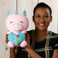 A woman holding a pink unicorn that is 10.5 inches tall while sitting holding valentine heart