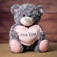 A gray bear that is 13.5 inches tall while sitting holding a pink Love You heart