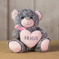 A gray bear that is 9 inches tall while sitting holding a pink heart that says "HUGS"