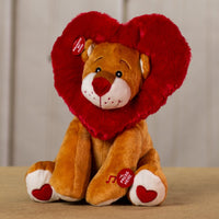 A tan lion that is 11 inches tall while sitting with a red heart wrapped around its head