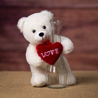 A standing white bear that is 8 inches tall while sitting holding a vase with a red Love heart wrapped around it
