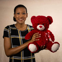 A woman holds a large red bear with white feet and snout
