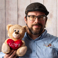 A man holds a beige Valentine's Day teddy bear that says LOVE on a heart