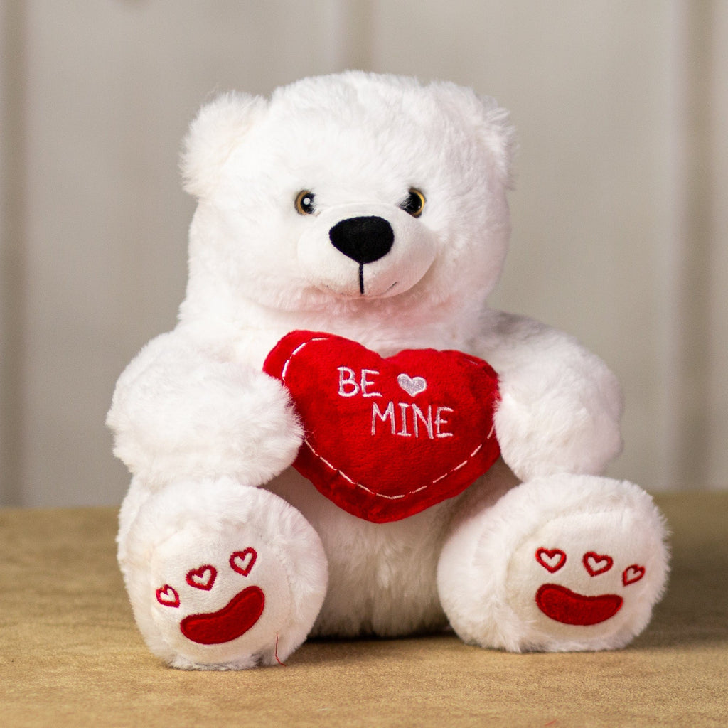 A white polar bear that is 10 inches tall while sitting holding a red "BE MINE" heart with embroidered red hearts on its feet