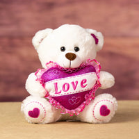A white bear that is 10 inches tall while sitting with glittery feet and ears holding a glittery pink "LOVE" heart